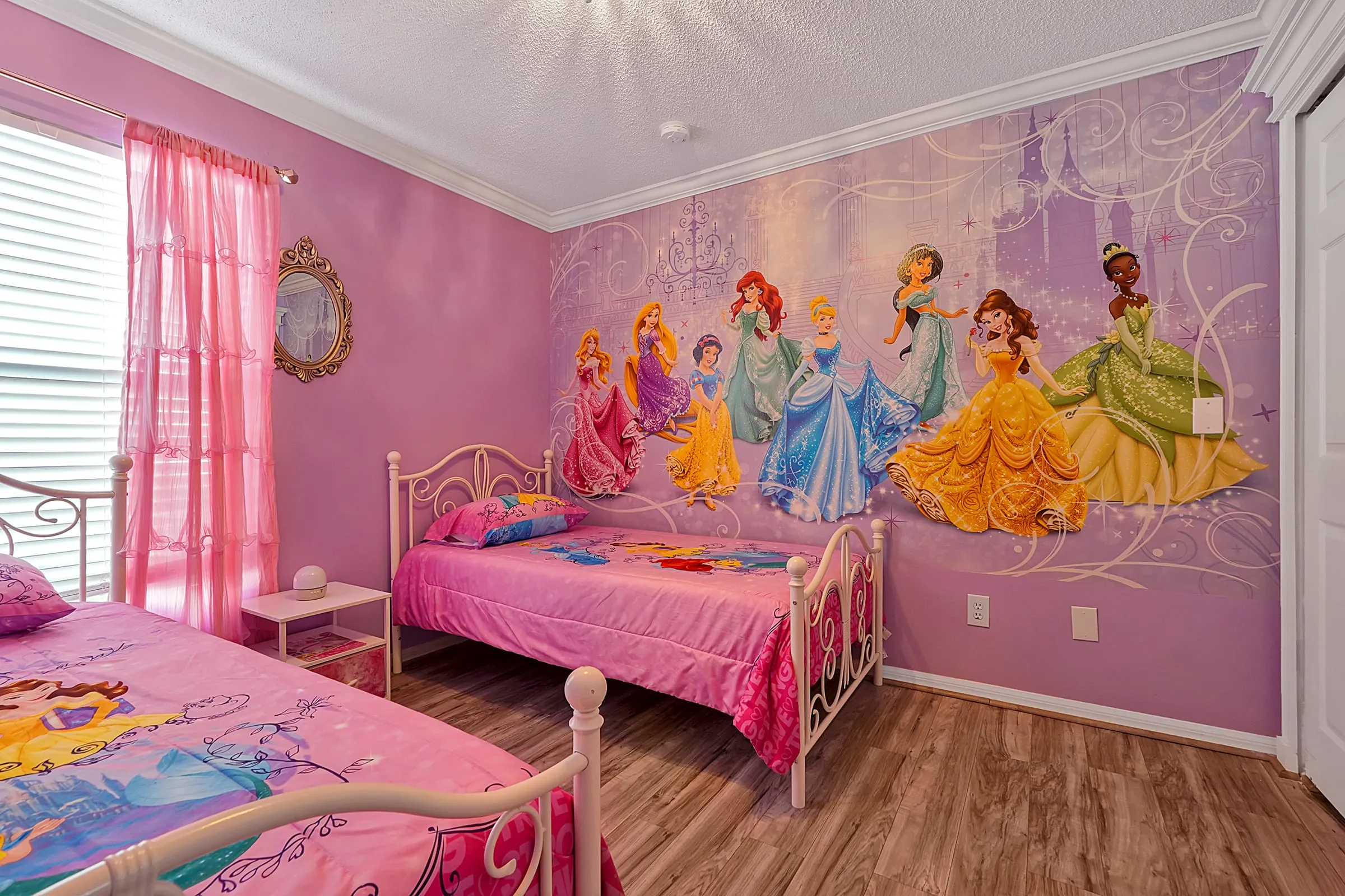 Princess-themed bedroom showing both twin beds and the castle mural