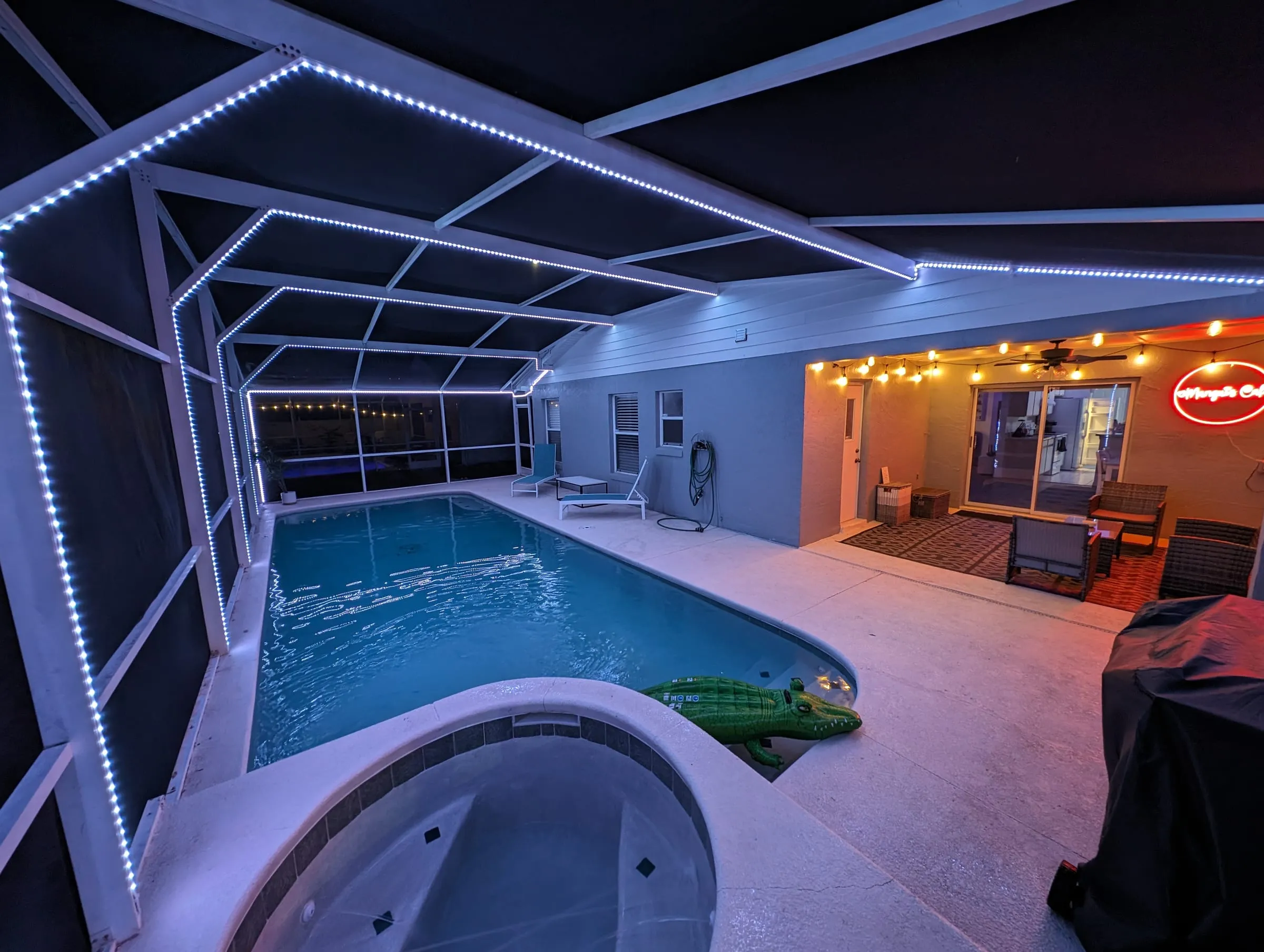 Pool deck at night with neon café sign and LED accent lighting