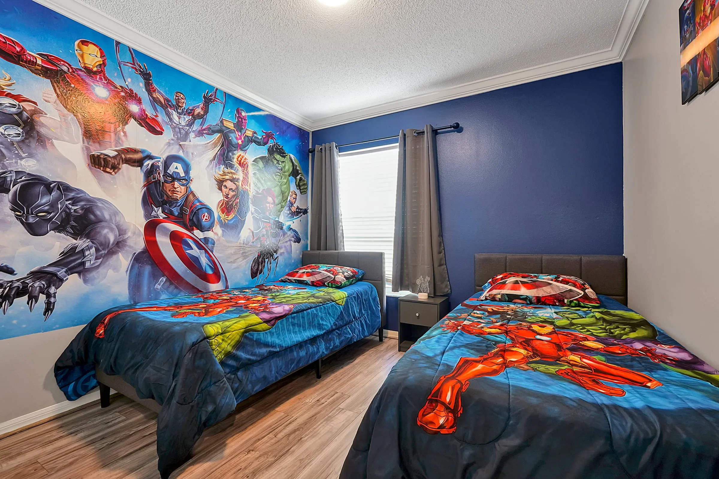 Super-heroes bedroom showing both twin beds and the back-wall mural